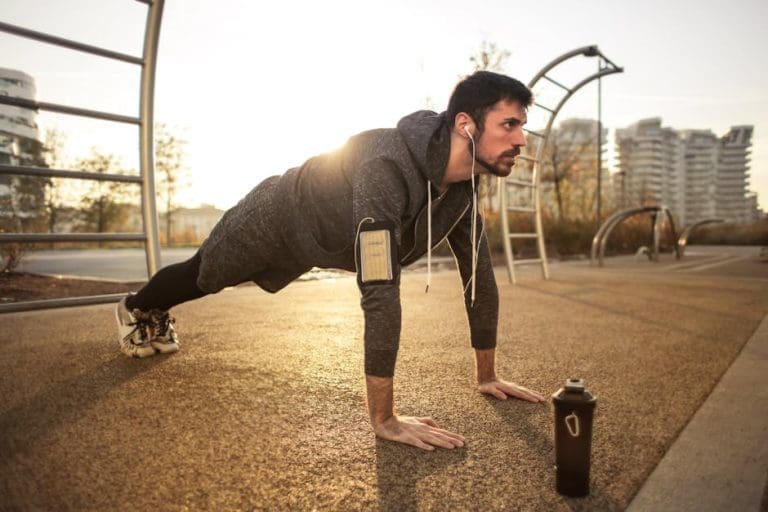 Man in Gray Jacket Doing Push-Ups During Sunrise